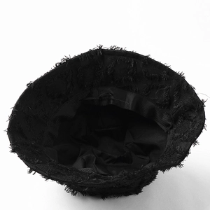 Close-up of black bucket hat featuring trendy frayed edges and distressed canvas texture