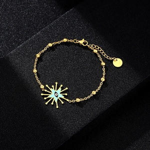 Macro detail of golden evil eye charm with sunburst pattern on stainless steel bead chain