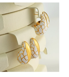 Détail de boucles d'oreilles émaillées dorées et blanches avec motif de fissure vintage