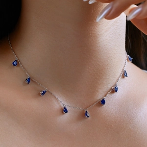 Close-up of blue teardrop pendant necklace on neck, featuring multiple elegant crystals