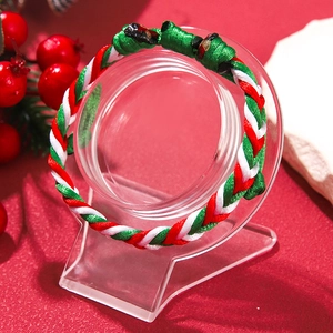 Detailed view of Christmas red, green, and white braided adjustable cord bracelet on red stand
