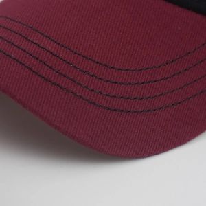 Close-up of burgundy cotton baseball cap brim with precise black quadruple stitching