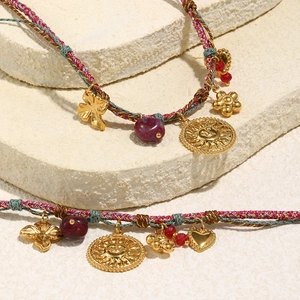 Detail of colorful woven bohemian bracelet with 18K gold sun pendants on a stone base
