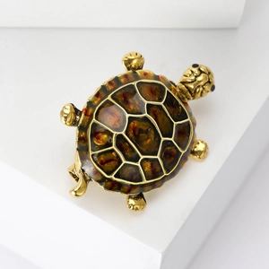 Detail of a vintage-style golden turtle brooch with brown enamel shell on white stand