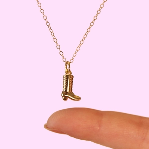 Golden cowboy boot pendant necklace on 18k gold plated chain with soft pink background