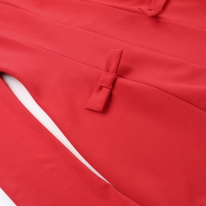 Dettaglio dell'abito rosso a trapezio con fiocchi decorativi e tessuto di alta qualità