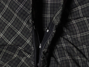Close-up of dark grey plaid fabric showing detailed waist zipper and metal hook fastener