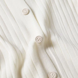 Detail shot of white ribbed knit fabric texture with decorative S logo button accents