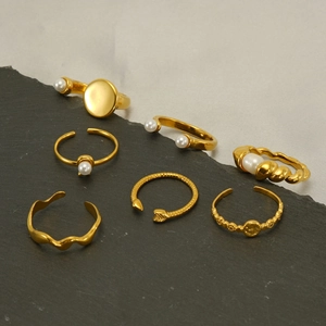 Set of 6 gold-plated stainless steel rings with pearls on dark stone and fabric base
