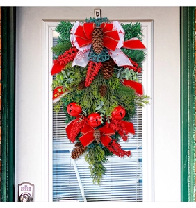 Detail of Christmas teardrop swag featuring red bow, pine cones, and metal bells on greenery