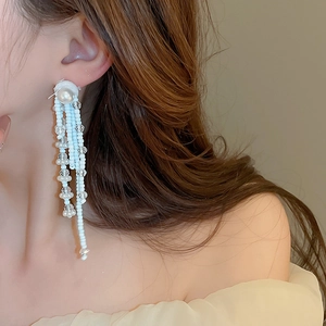 Elegant multi-layered tassel earrings with white pearls and beads on a model