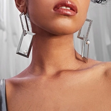 Detailed view of silver rectangular layered earrings with a white pearl on model
