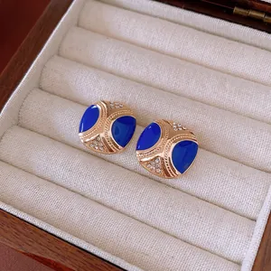 Vintage gold square earrings with deep blue enamel and sparkling crystals in a jewelry box