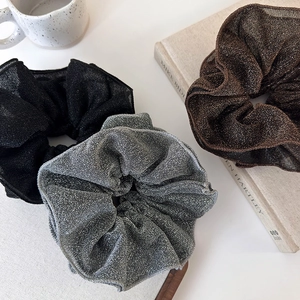 Three elegant shimmering scrunchies in black, silver grey and bronze colors for stylish hair