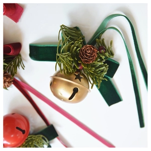 Close-up of Christmas bell ornaments with velvet bows, pine cones and needles