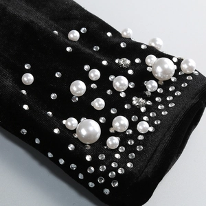 Detail of black velvet dress featuring elegant white pearls and sparkling crystal rhinestones