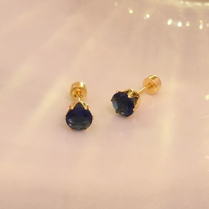 Détails de boucles d'oreilles dorées avec zircon bleu foncé et fermoir à vis