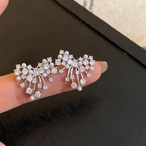 Macro shot of silver fireworks studs with sparkling zircons and delicate mini pearls