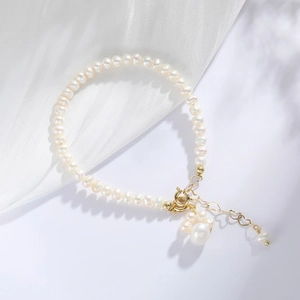 Detailed macro view of 14K gold-plated clasp with heart pendant and baroque pearl charm