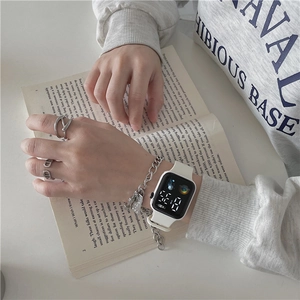 Close-up of white LED square watch paired with silver CD rings and thick chain jewelry