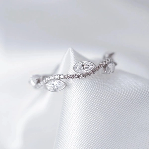 Detalle de anillo de hojas con circonitas sobre fondo de seda blanca elegante