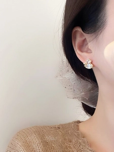 Detail of elegant gold plated gourd stud earrings with zircons worn by a model