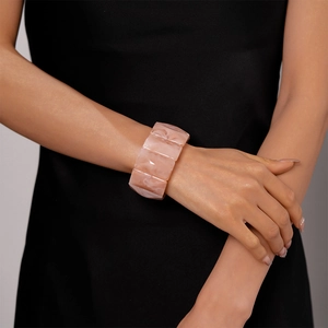 Detail of pink marble-pattern acrylic wide bangle bracelet worn on a model's wrist