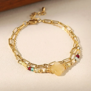 Detailed close-up of double-layer beaded bracelet with yellow flower pendant and gold link chain