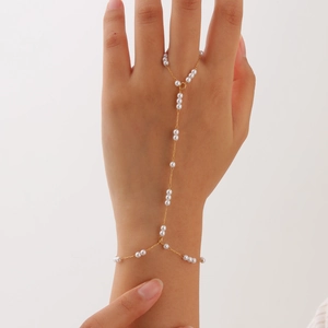 Detail of a golden double-layered slave bracelet featuring elegant white pearls on hand