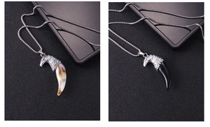 Detailed close-up of eagle head pendants with curved ivory and black imitation fangs