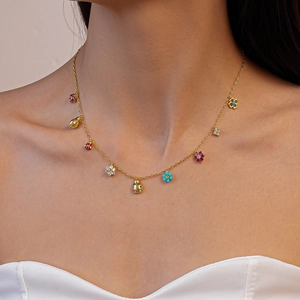 Close-up of golden ladybug and flower charms necklace with colorful zircon on collarbone