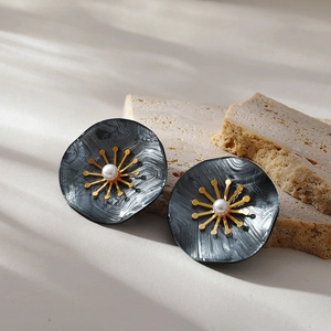 Detail of dark marble resin flower earrings with gold center and pearl on stone