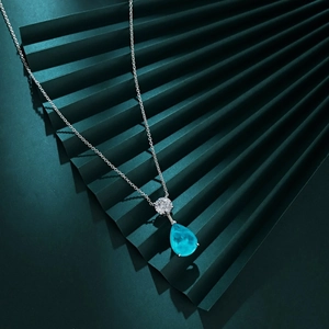 Elegant sterling silver necklace featuring a blue pear-cut gemstone pendant on a green fan