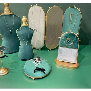 Detail of dark green velvet necklace bust stand with elegant gold metal trim and screen