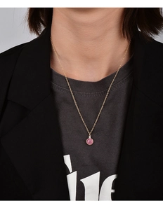 Detail shot of a minimalist gold necklace with pink round gemstone on a model