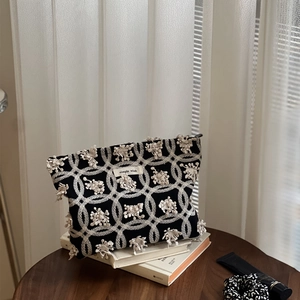 Détail d'une pochette en toile noire avec broderie florale 3D et étiquette simple