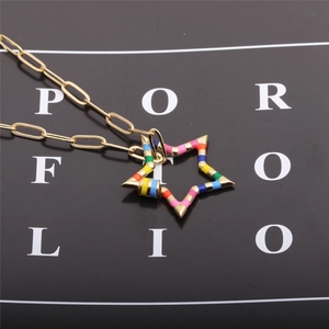 Detailed shot of a gold chain necklace with a colorful striped star enamel pendant
