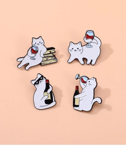 Detail view of 4 cute enamel pins featuring white cats with wine on an orange background
