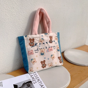 Detail of canvas tote with pink plush handles and cute bear patterns on a wooden bench