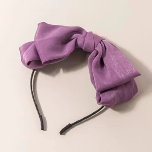 Detail of purple satin headband featuring a large bow on a slim black band