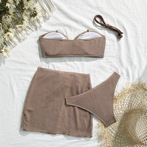 Detailed flat lay of beige ribbed knit three-piece bikini set with a beach skirt and hat