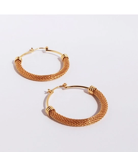 Close-up of golden woven mesh texture on large round hoop earrings with snap closure
