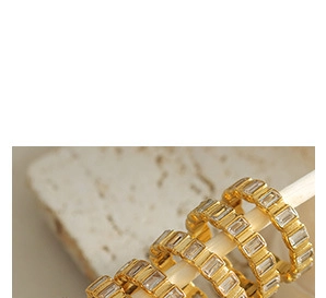 Detail of 18k gold plated chain jewelry with baguette cut zircon inlay on white stand