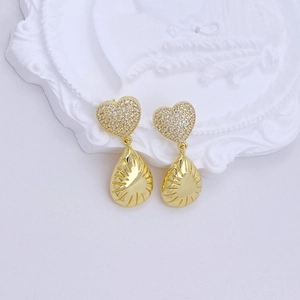 Detail of gold heart earrings with water drop pendants on a white vintage tray