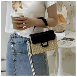 Detail of hand-woven straw box bag with pleated leather handle and gold twist lock