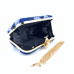 Detail of blue embroidered clutch with gold floral clasp, lining and chain strap