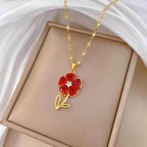 Detail of red flower pendant with gold leaves and crystals in a beige jewelry box