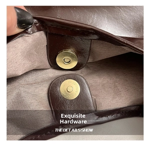 Detailed close-up of a golden magnetic closure on a vintage leather tote bag