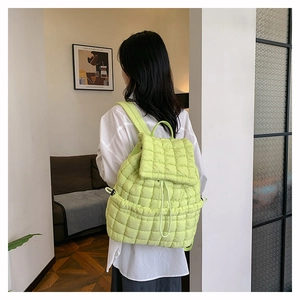 Vista posteriore di una modella con zaino trapuntato verde chiaro in stile piumino soffice