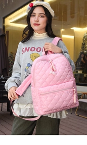 Dettaglio dello zaino trapuntato rosa con texture imbottita e tirante con nodo
